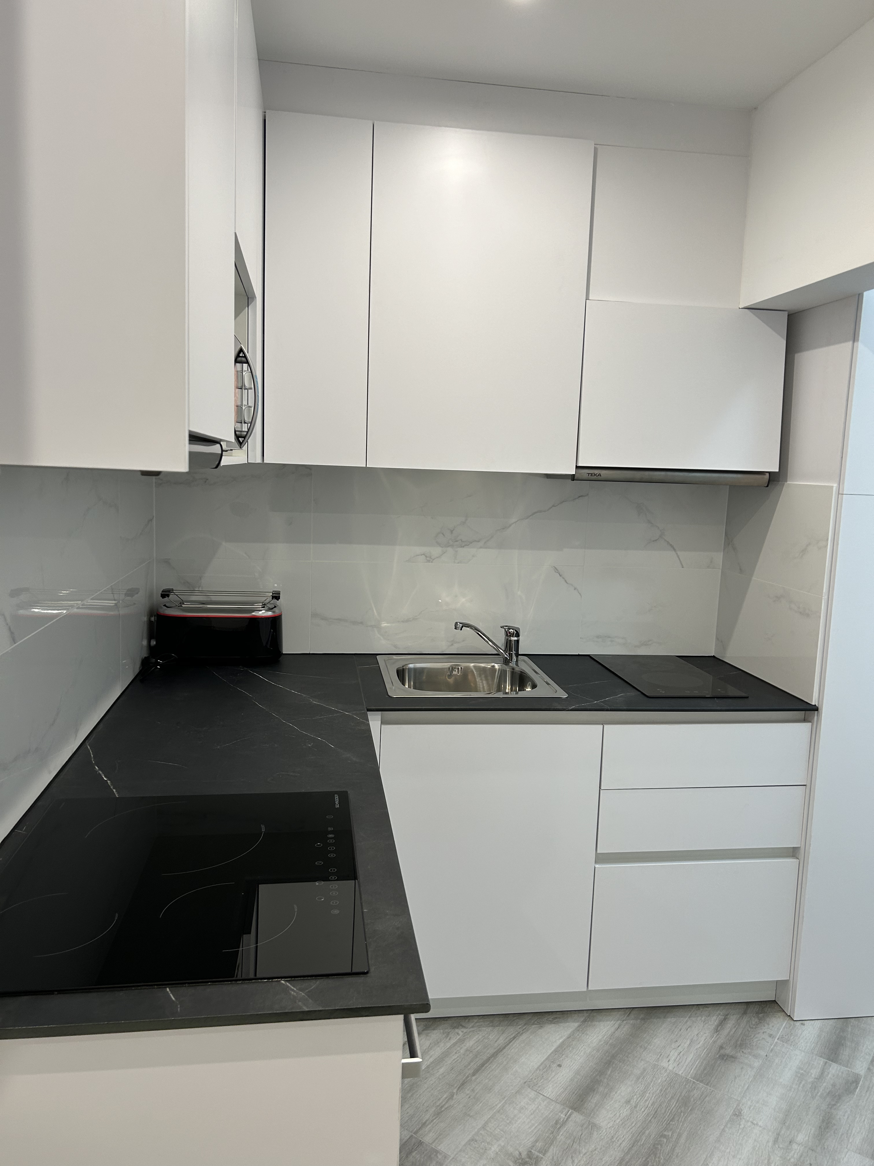 Cocina moderna con muebles blancos y encimera negra