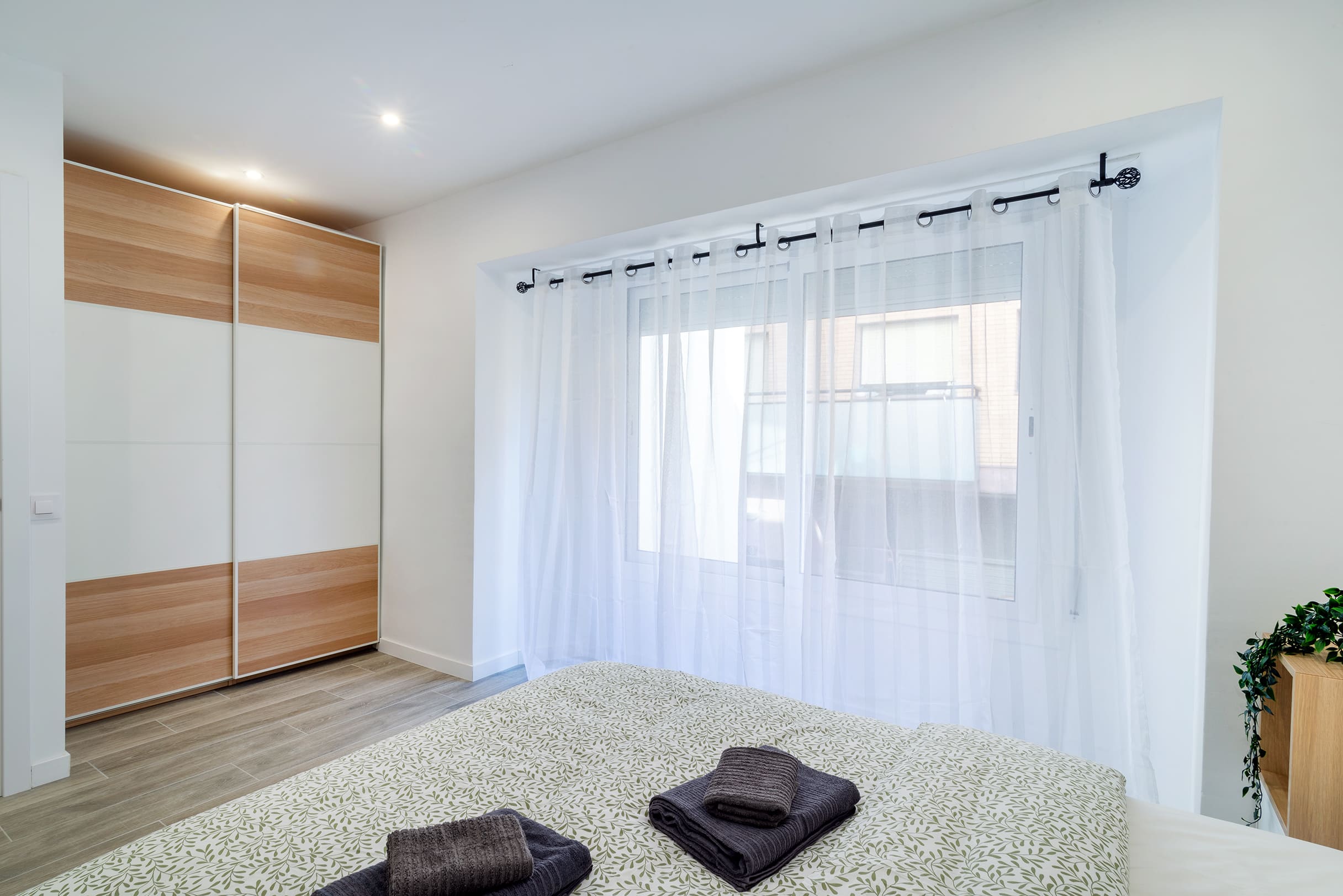 Dormitorio con armario empotrado y cortinas blancas